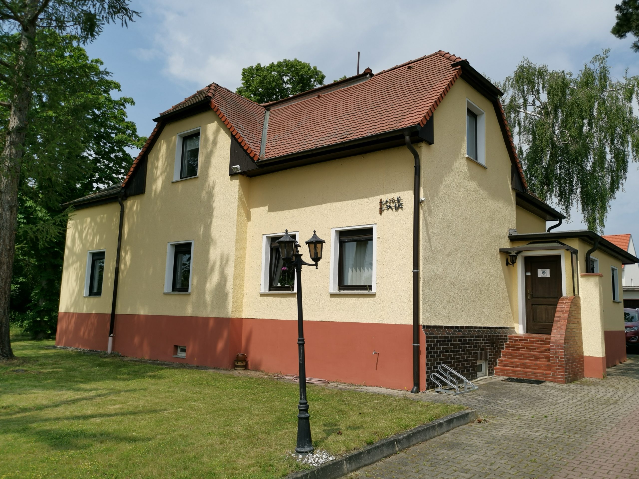 Das Firmenhaus von Schwerdtner Immobilien mit ockergelber Fassade, Ziegeldach und Vorgarten in Schkeuditz